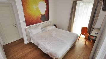 A hotel room with a bed, a desk, and a chair.