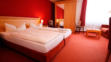 A hotel room with two beds, a desk, a chair, and a red carpet.