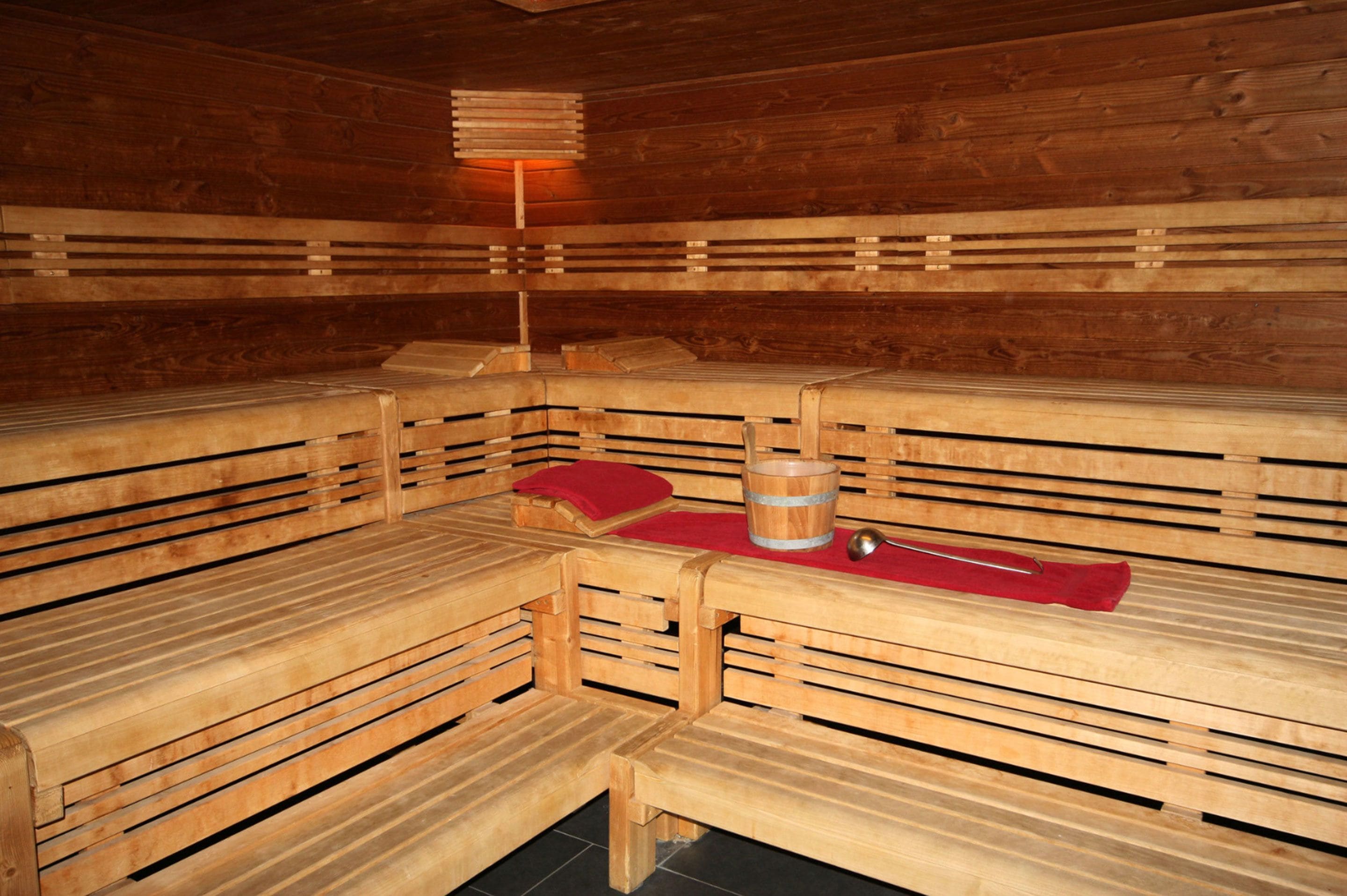 Una sauna con bancos de madera y una tina de madera en el centro.