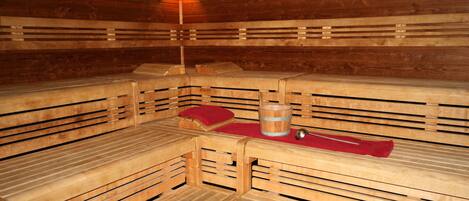 Una sauna con bancos de madera y una tina de madera en el centro.