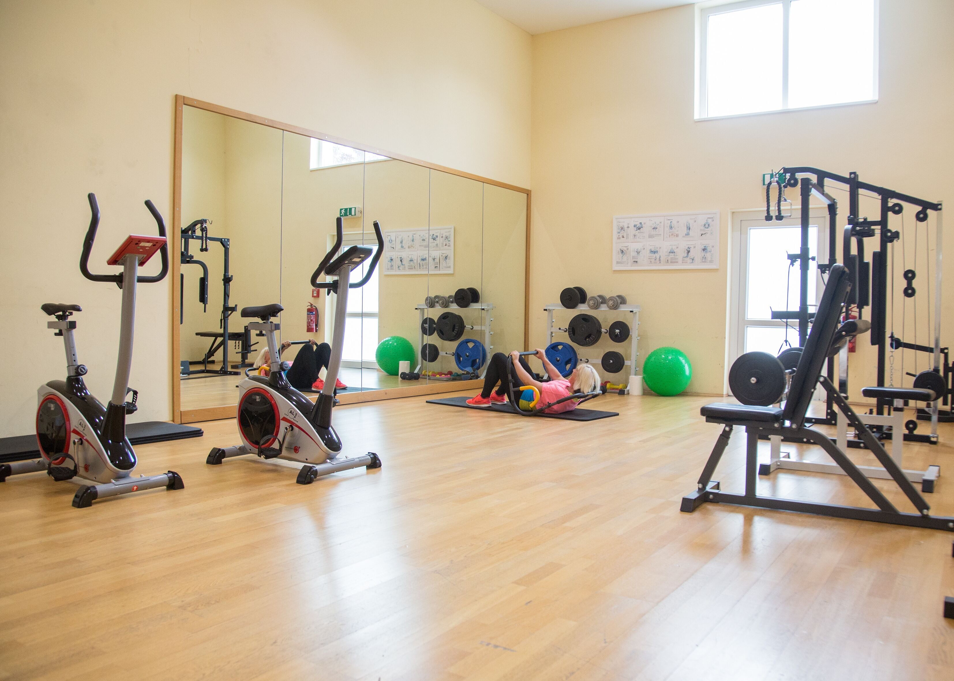 Un gimnasio con equipo de ejercicio, un espejo y una ventana.