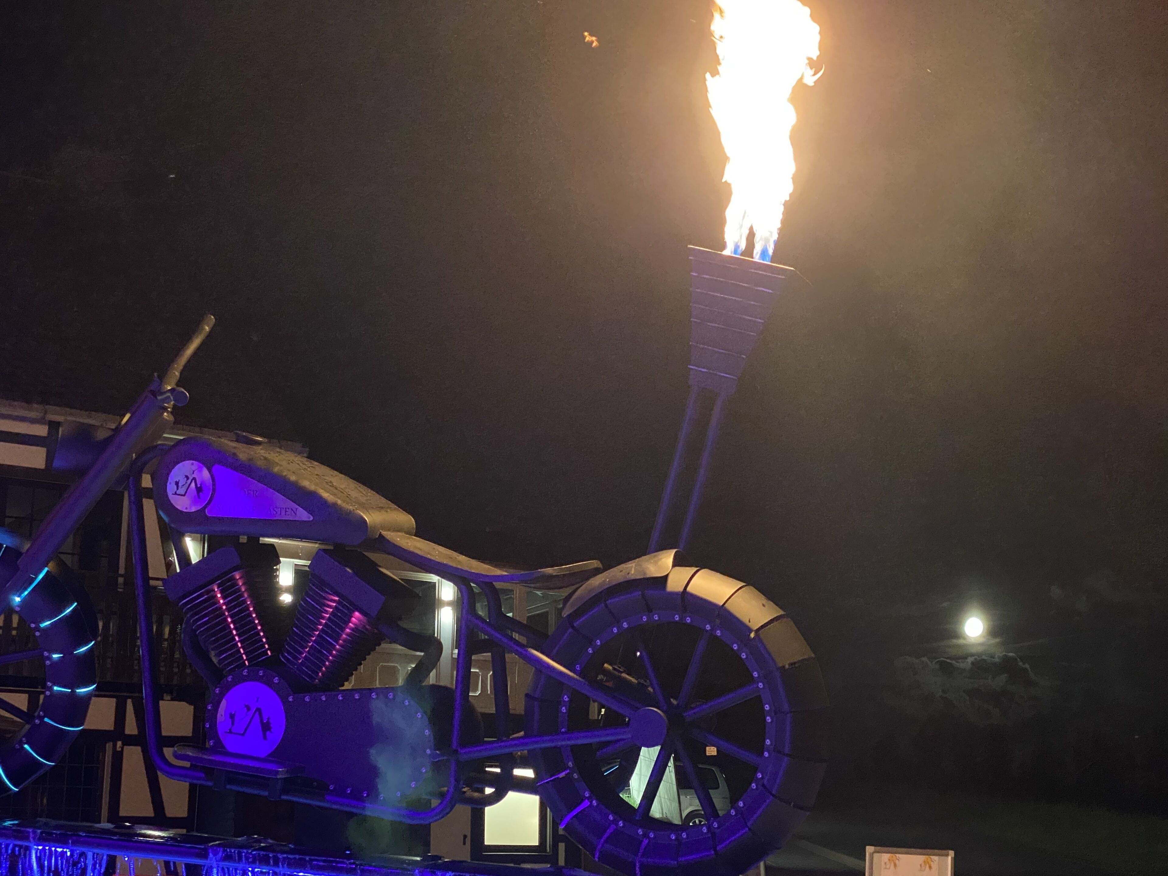 Ein Motorrad mit großem Rad und einer Flamme oben drauf, vermutlich für eine Show oder Veranstaltung.