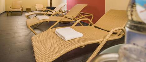 Una habitación con sillones de mimbre, una palmera y una pared de acento roja.