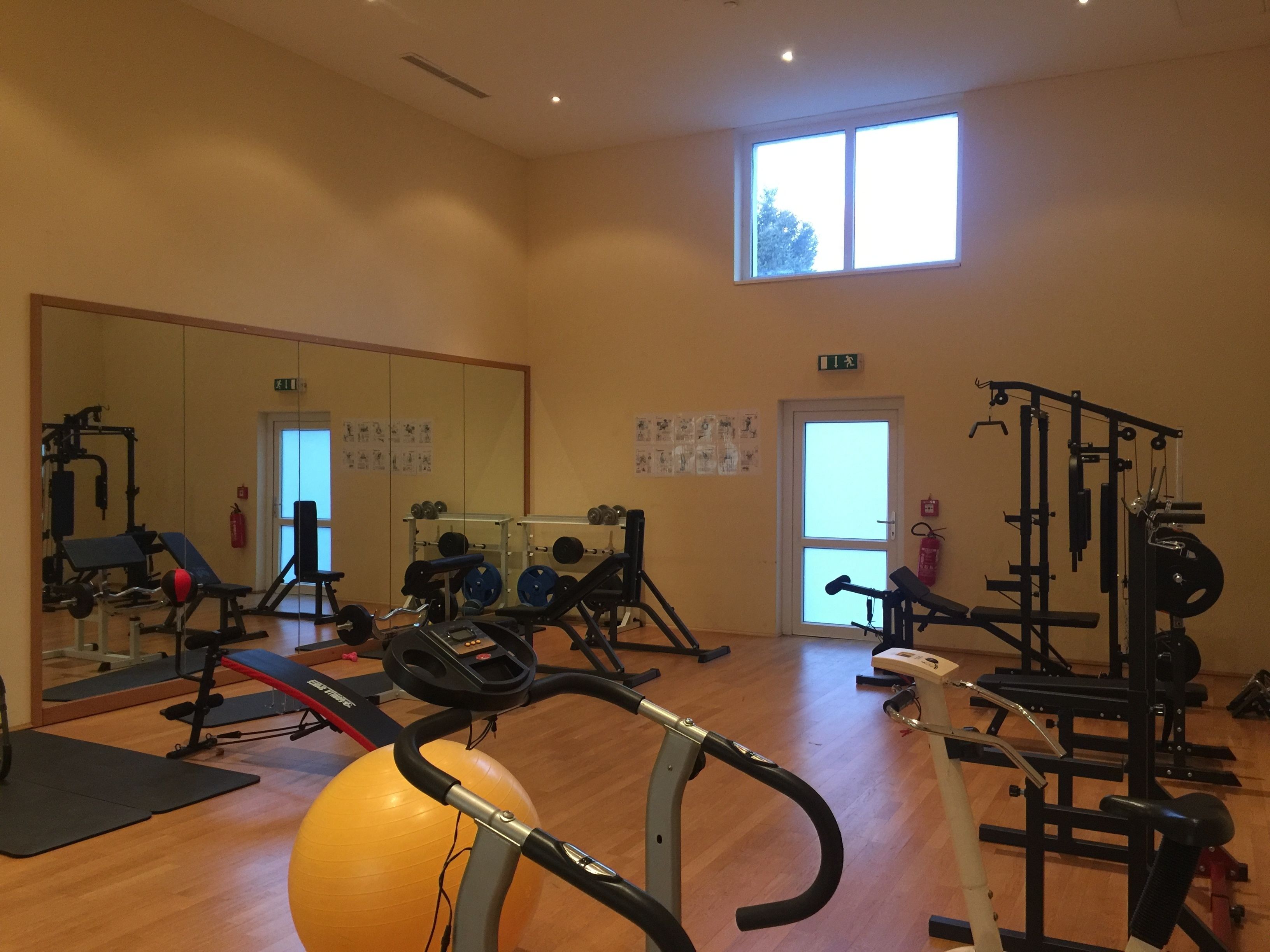 A gym with exercise equipment, a large mirror, and a window.