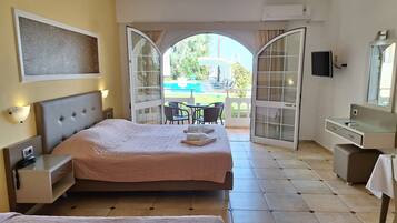 Ein Hotelzimmer mit einem großen Bett, einem Schreibtisch, einem Stuhl und einem Balkon mit Blick ins Freie.