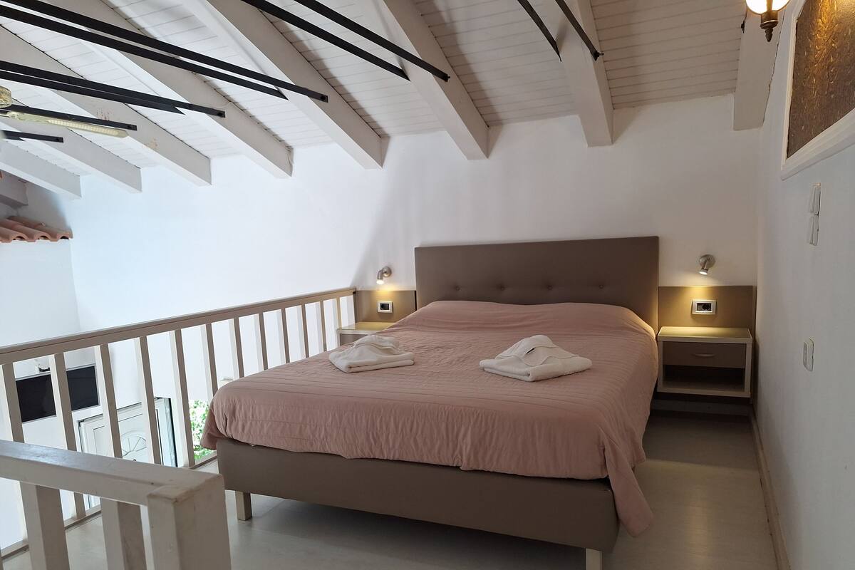 A bedroom with a bed, nightstands, and a balcony.