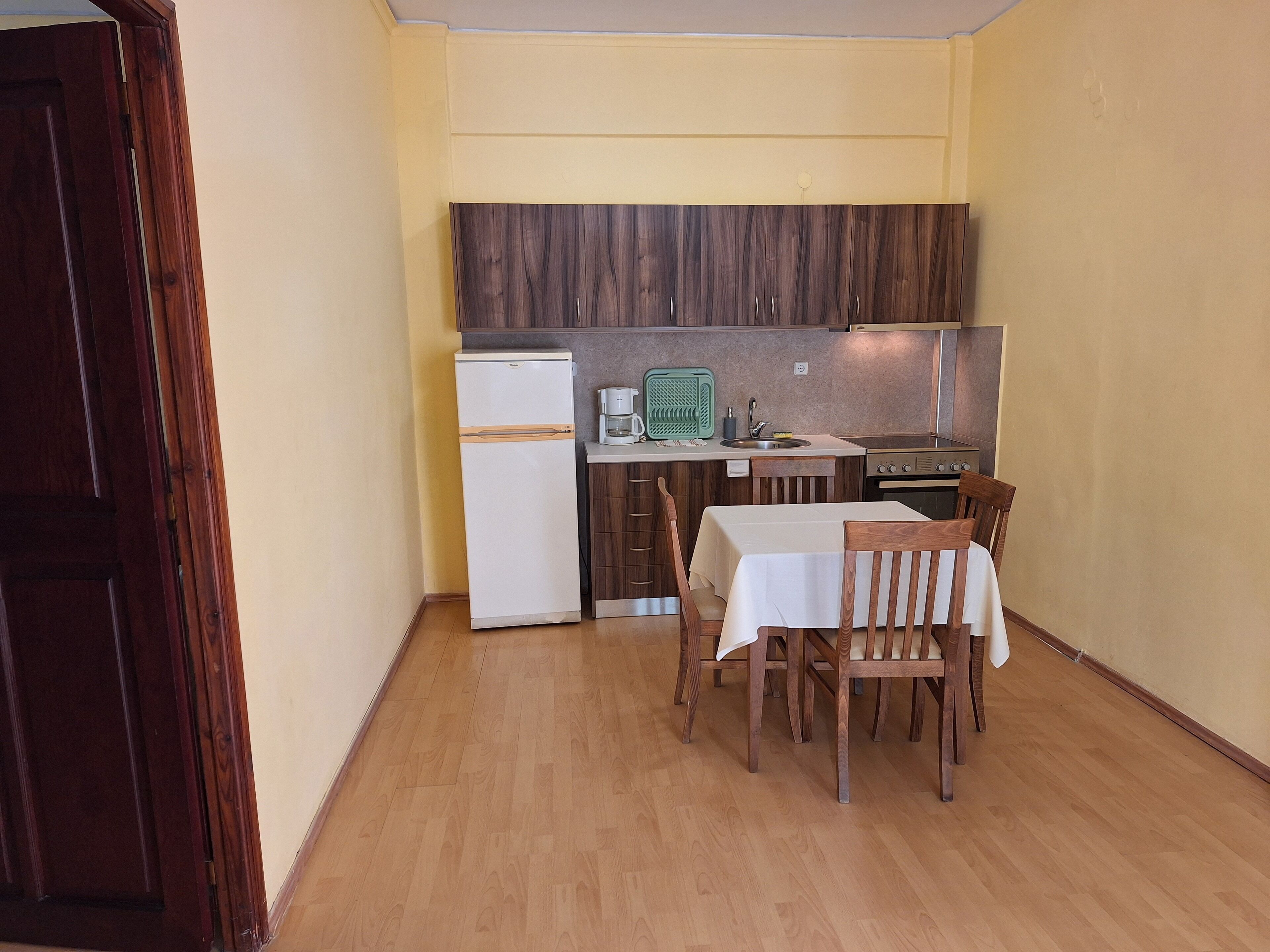 Una cocina compacta con refrigerador, estufa y mesa de comedor con sillas.