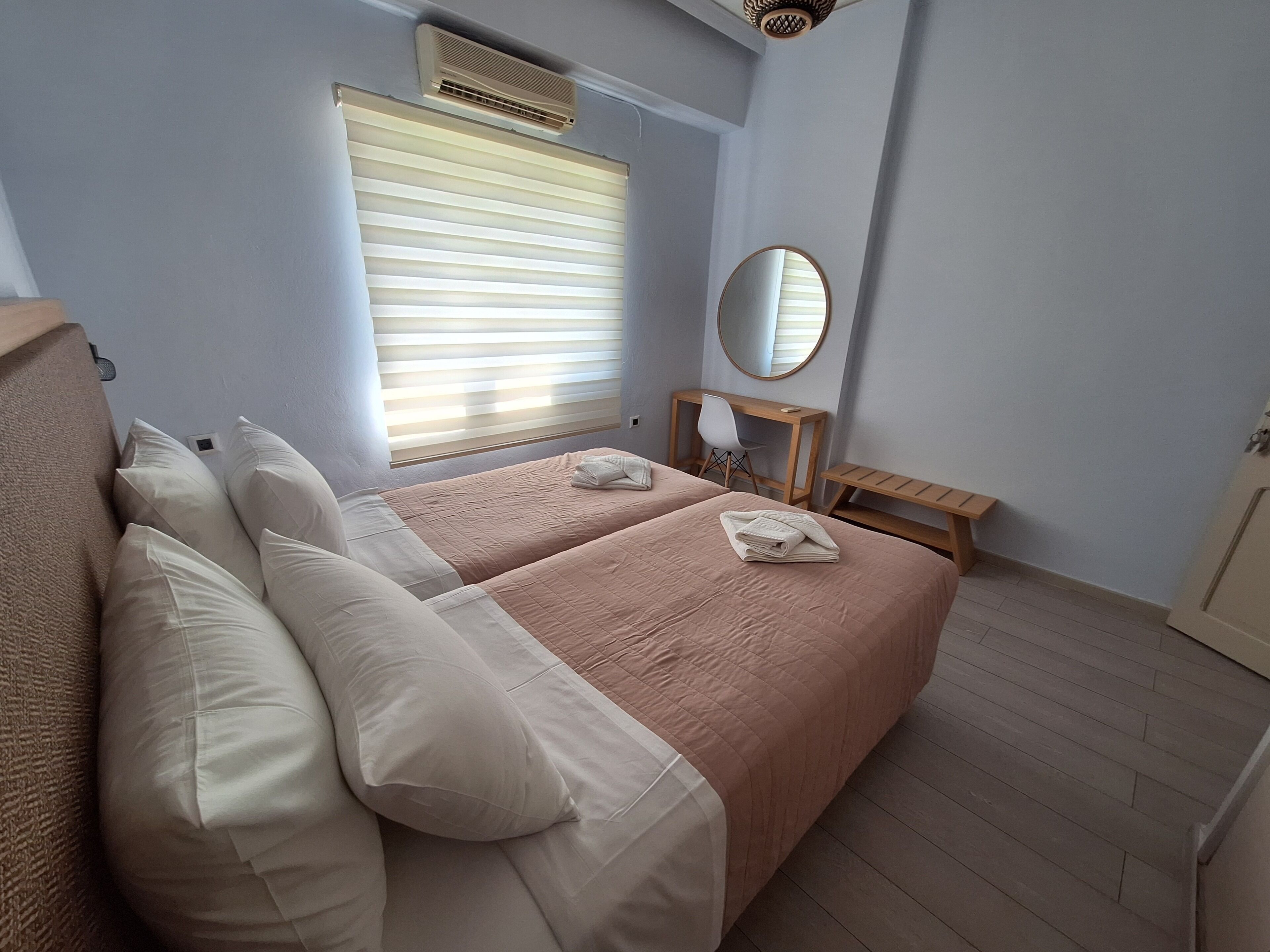Un dormitorio con dos camas, un escritorio, una silla y un espejo.