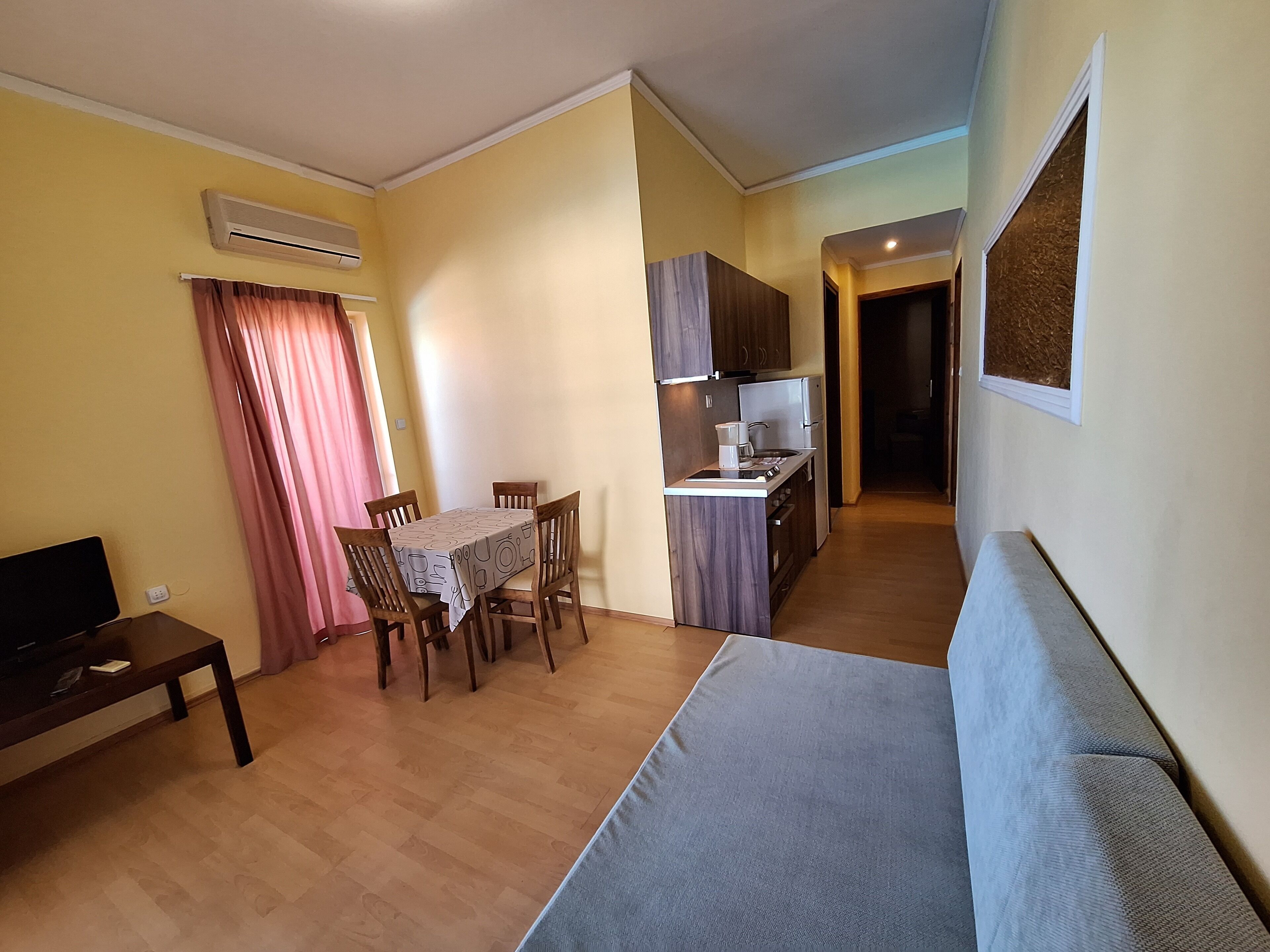 A compact living space with a dining area, kitchenette, and a sofa.