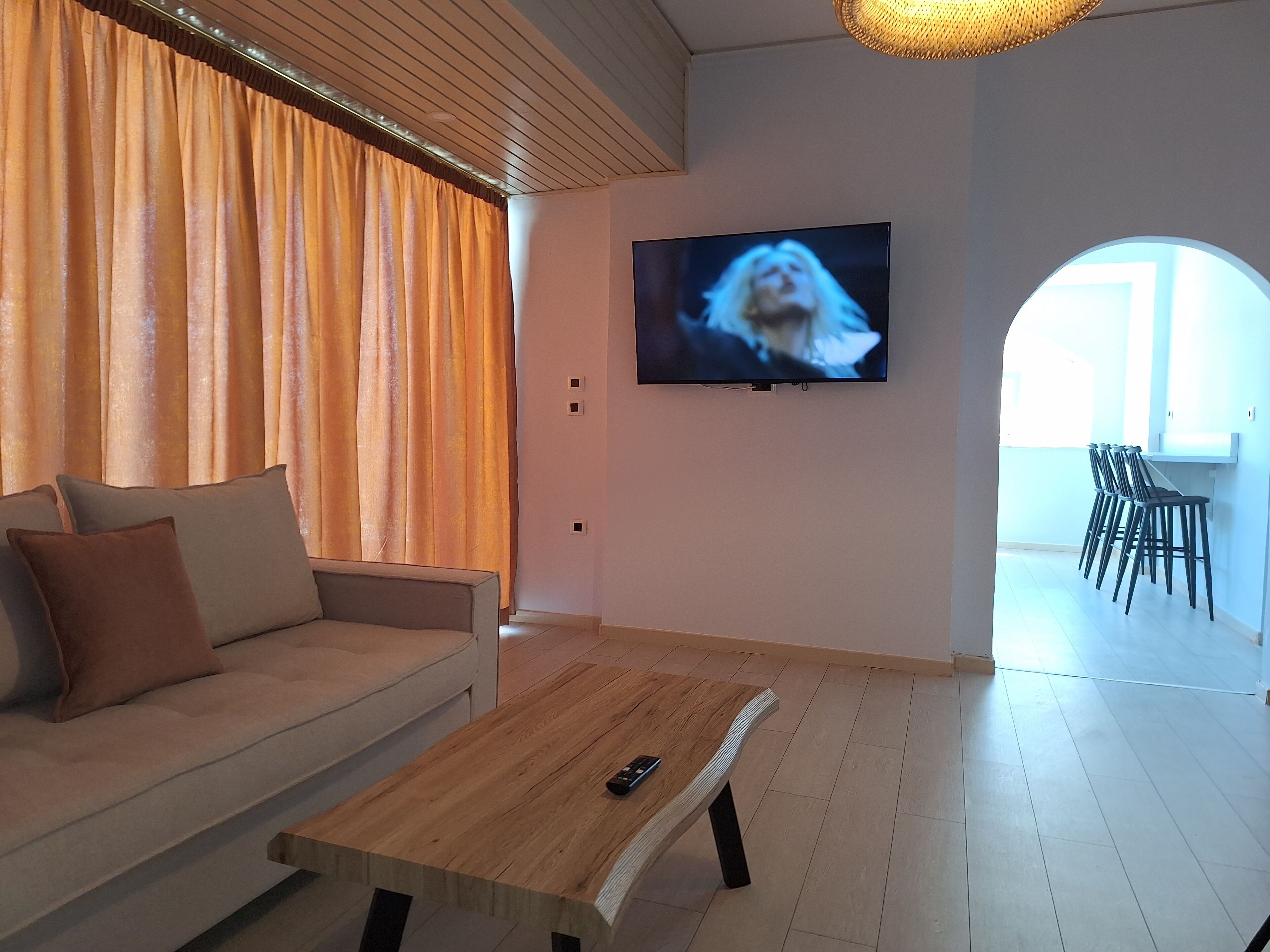 A modern living room with a sofa, a coffee table, and a TV mounted on the wall.