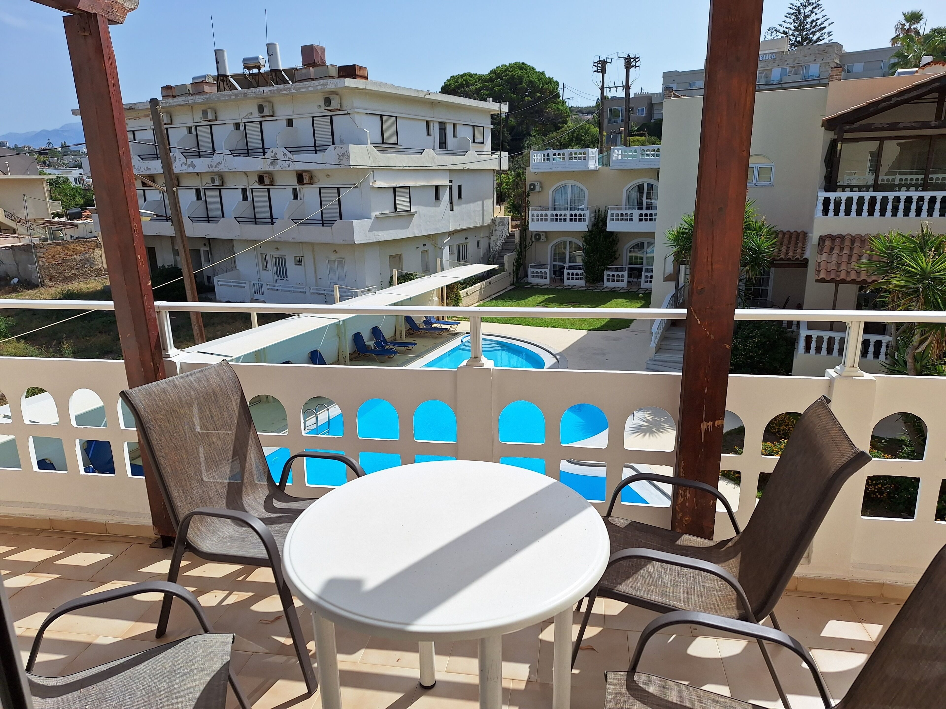 A balcony with a pool, chairs, and a table.