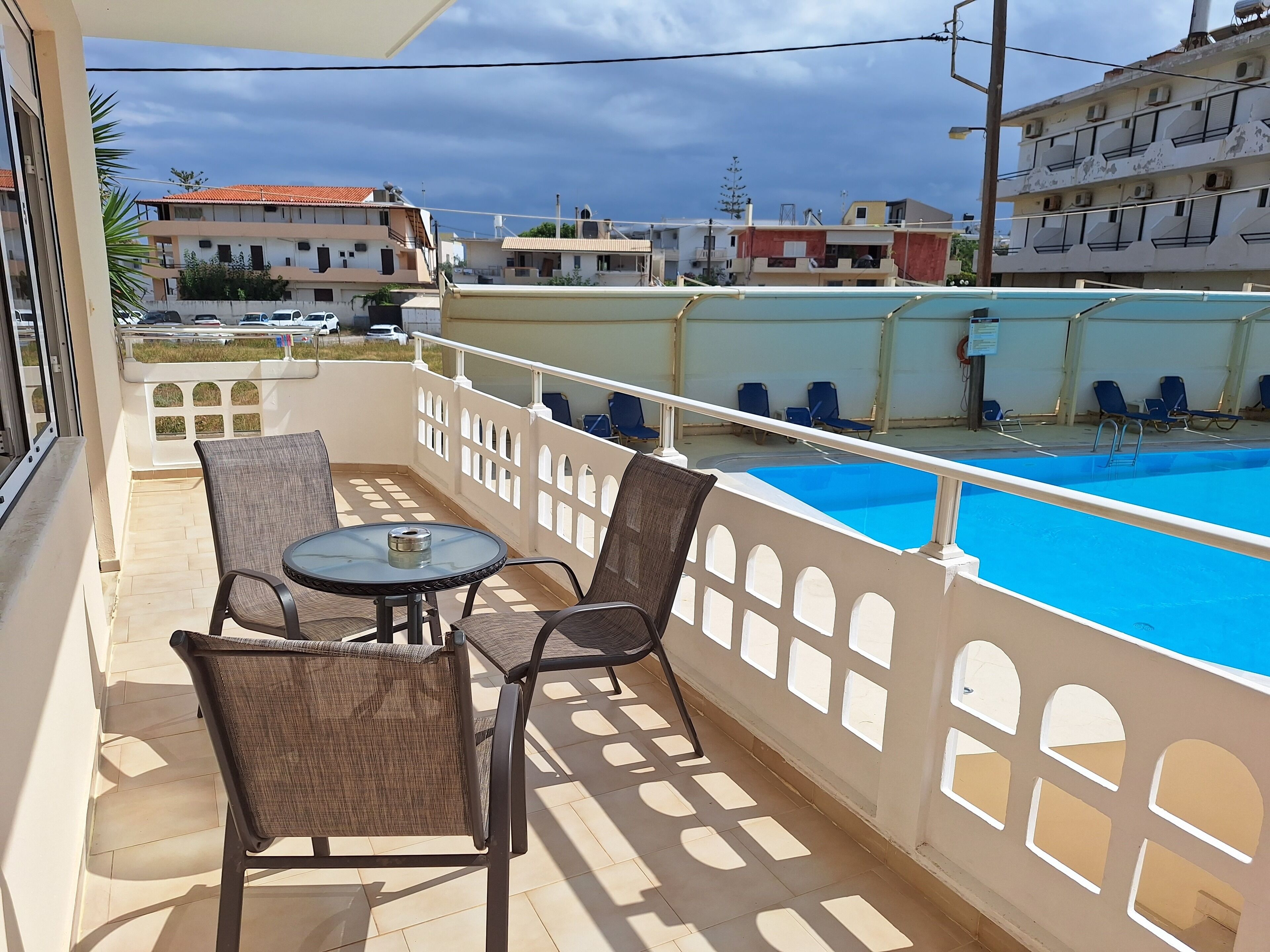 Un balcón con piscina, sillas y una mesa.