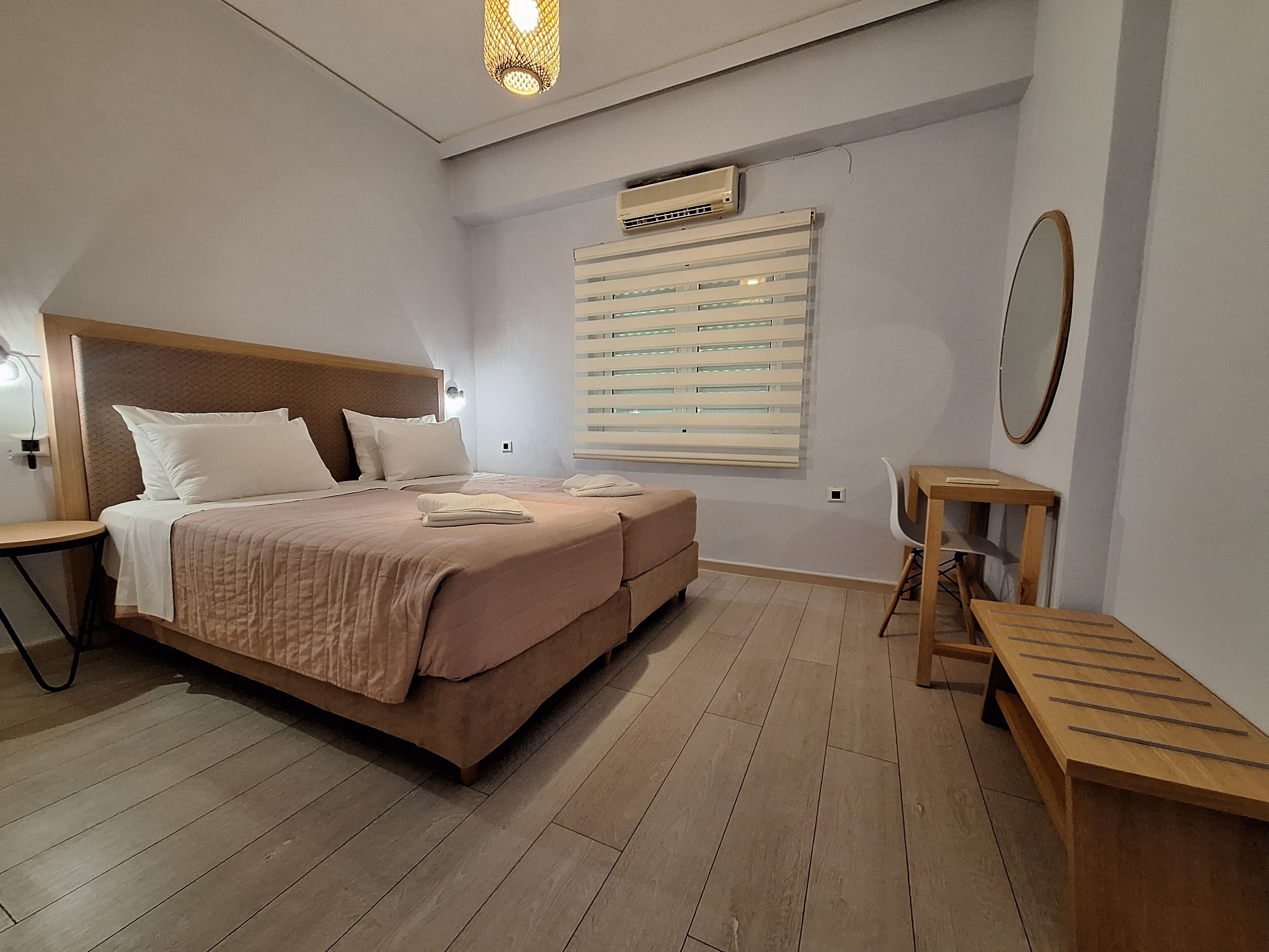 A bedroom with a bed, bedside tables, a mirror, and a window with blinds.