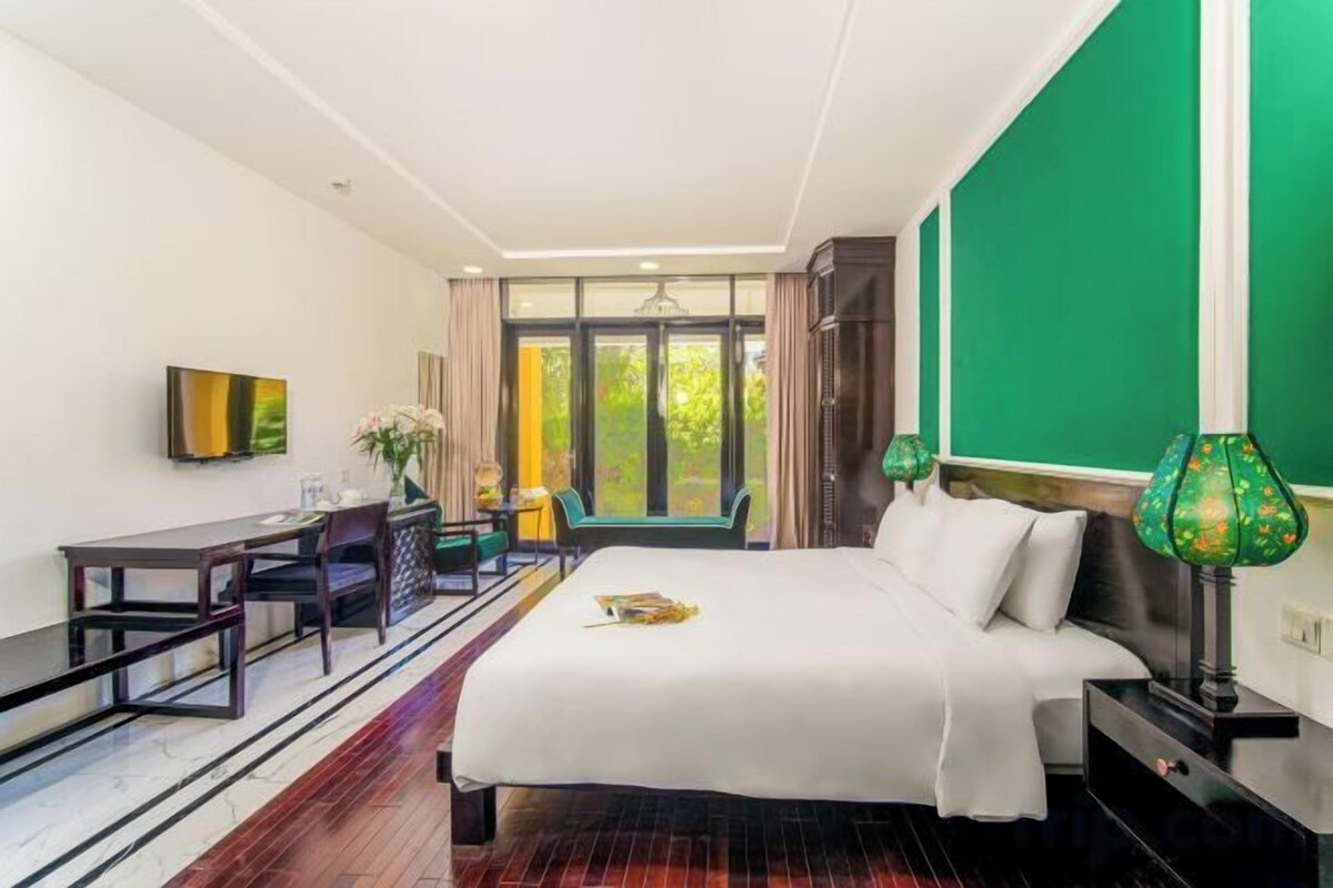 Una habitación de hotel con una cama, un escritorio, una silla, un televisor y una ventana con cortinas.