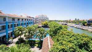 A hotel with a pool, palm trees, and a river view. - Thanh Binh Riverside Hotel (Da Nang)