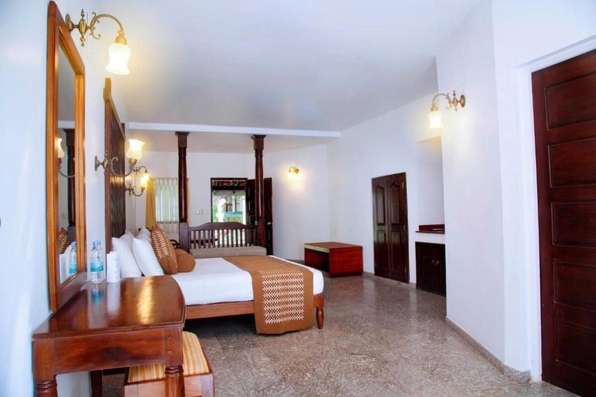 A hotel room with a large bed, a wooden dresser, a mirror, and a door.