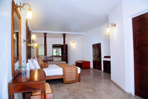 Une chambre d’hôtel avec un grand lit, une commode en bois, un miroir et une porte.