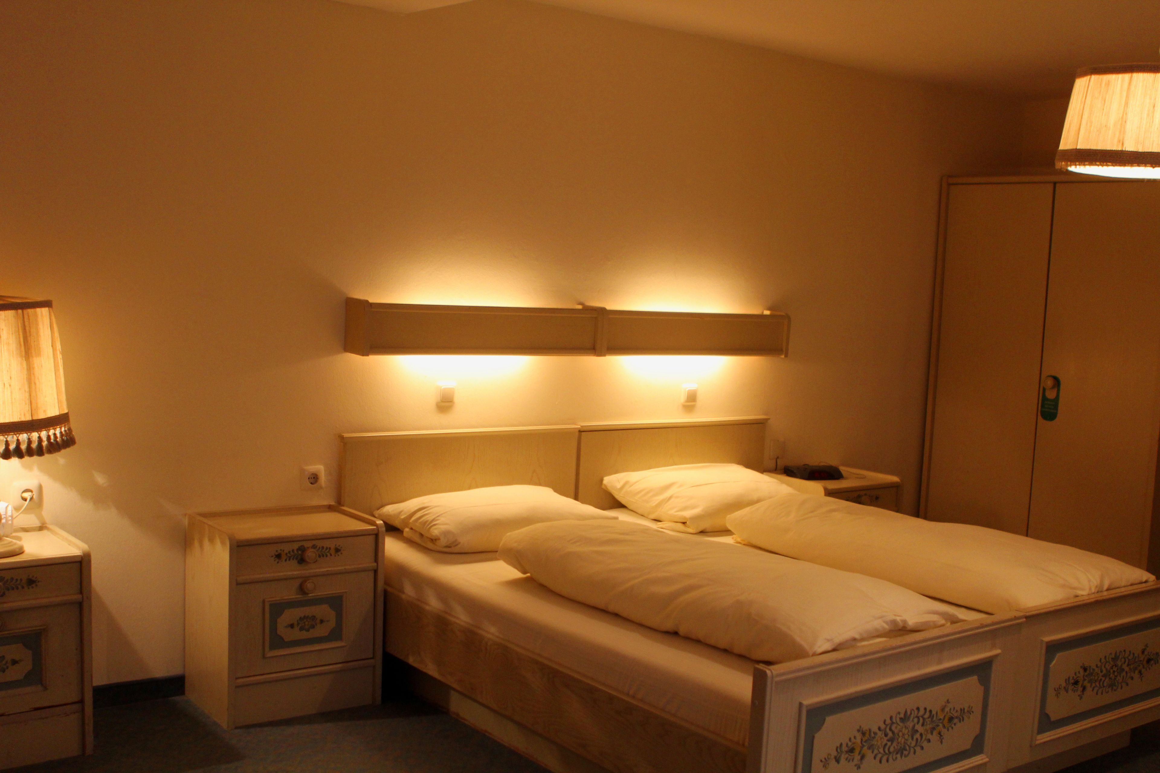 A double bed with a wooden headboard and two bedside tables, each with a drawer and a lamp.