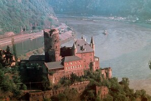 Un castillo histórico con una torre destacada, ubicado junto a un río con barcos.