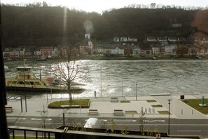 Un paseo fluvial con bancos, un muelle para barcos y edificios a lo largo de la orilla.