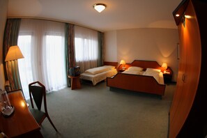 Una habitación de hotel con una cama, mesitas de noche, un escritorio, una silla y una lámpara.