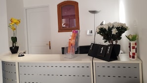 En receptionsdisk med en vit bardisk, en spegel med träram ovanför och ett genomskinligt plastställ som håller en tidning.