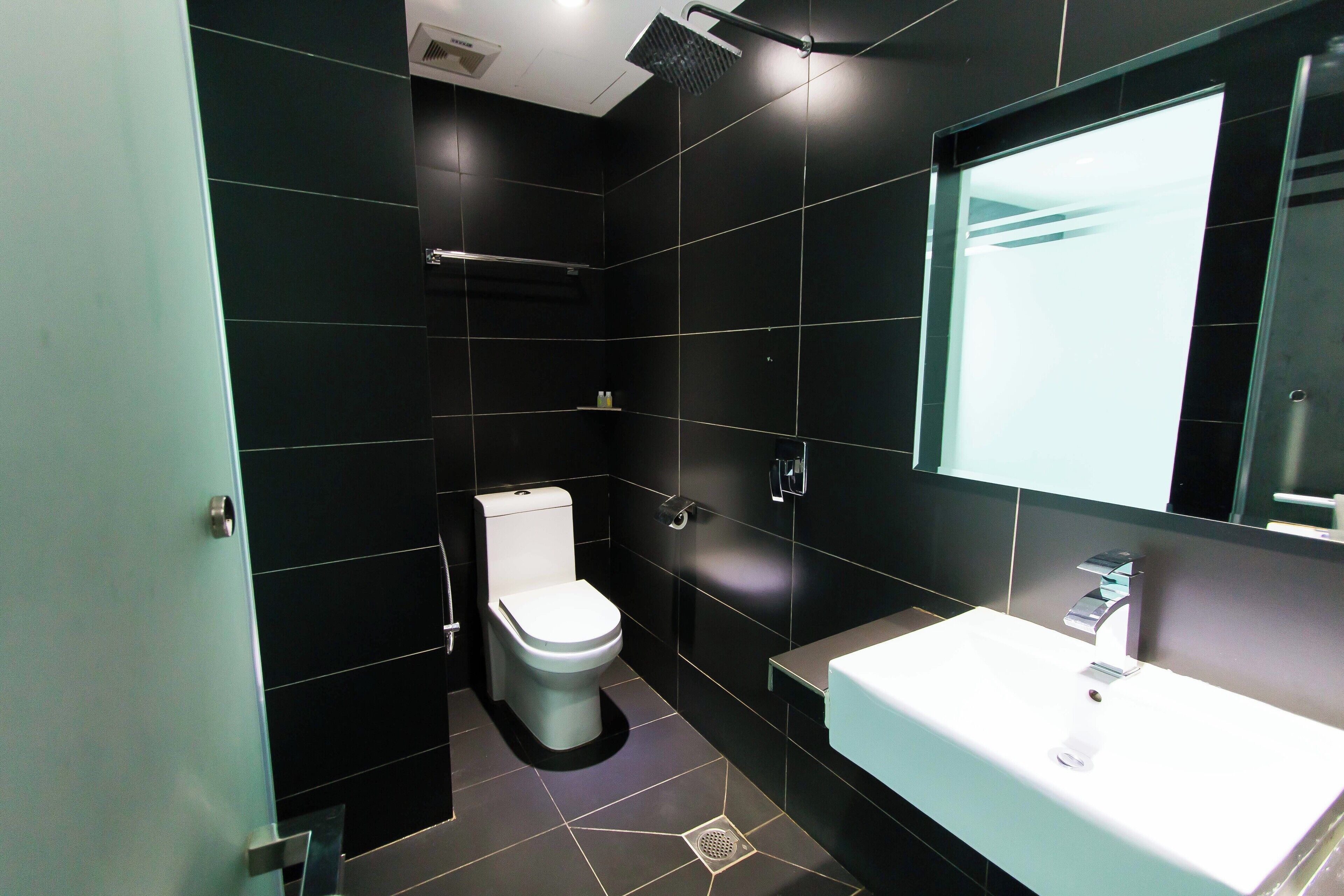 A modern bathroom with a white toilet, a sink, and a shower.