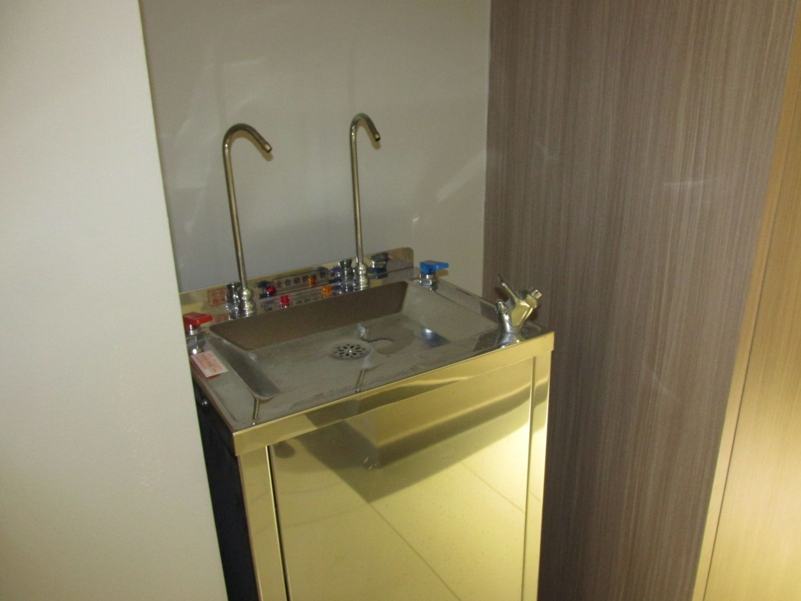 Un baño con tocador dorado, un lavabo con dos grifos y un espejo sobre el lavabo.
