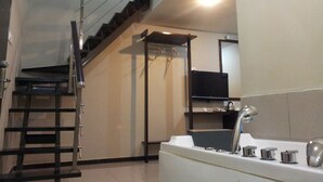 Een trap die naar een bovenverdieping leidt, een keuken met een spoelbak en kraan, en een flatscreen televisie aan de muur bevestigd.