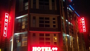 Een hotel met een opvallend neonbord waarop 'HOTEL99' staat en een zichtbare ingang.