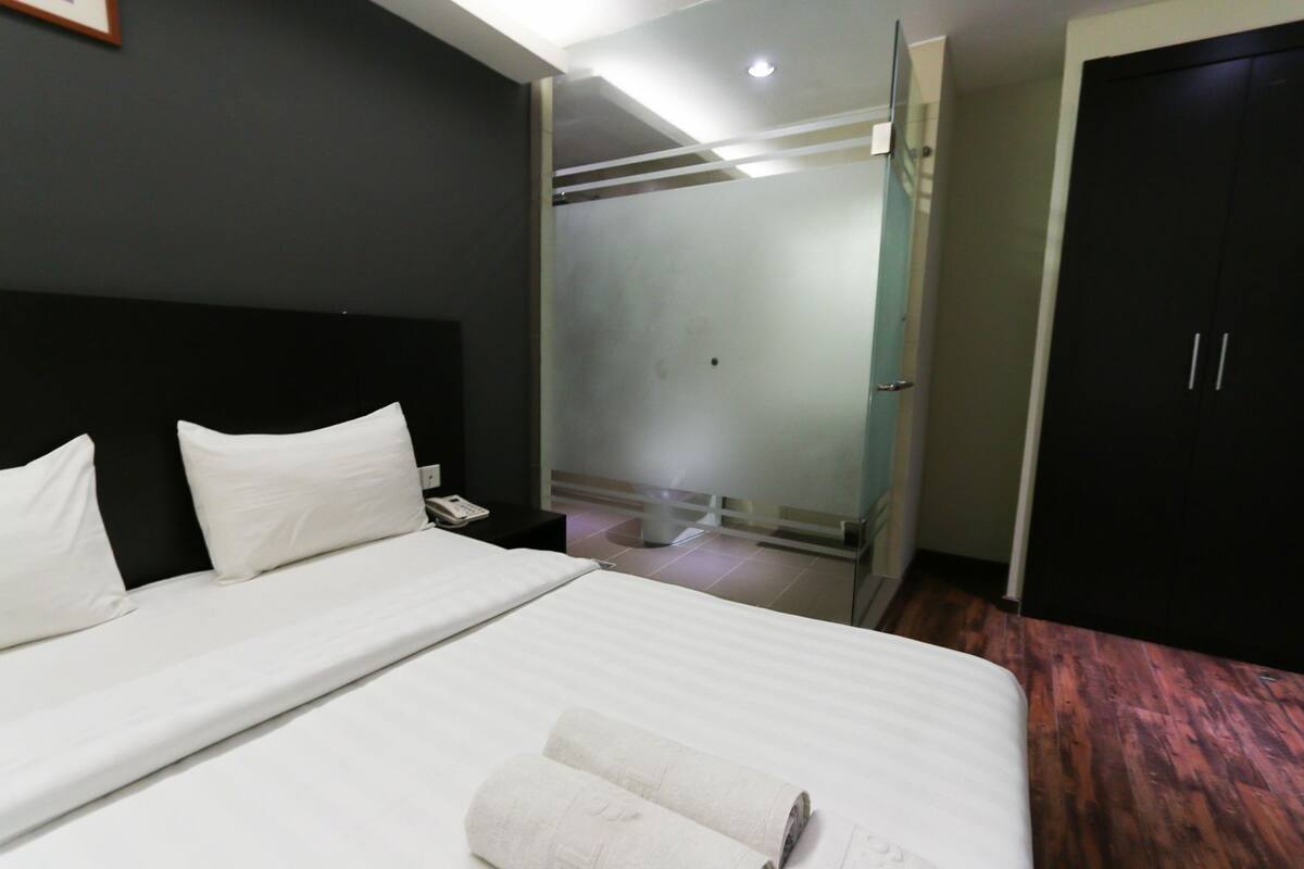 A hotel room with a bed, a nightstand, a phone, a mirror, and a wardrobe.