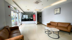 A hotel reception area with a reception desk, two leather sofas, a marble coffee table, and a framed artwork on the wall.