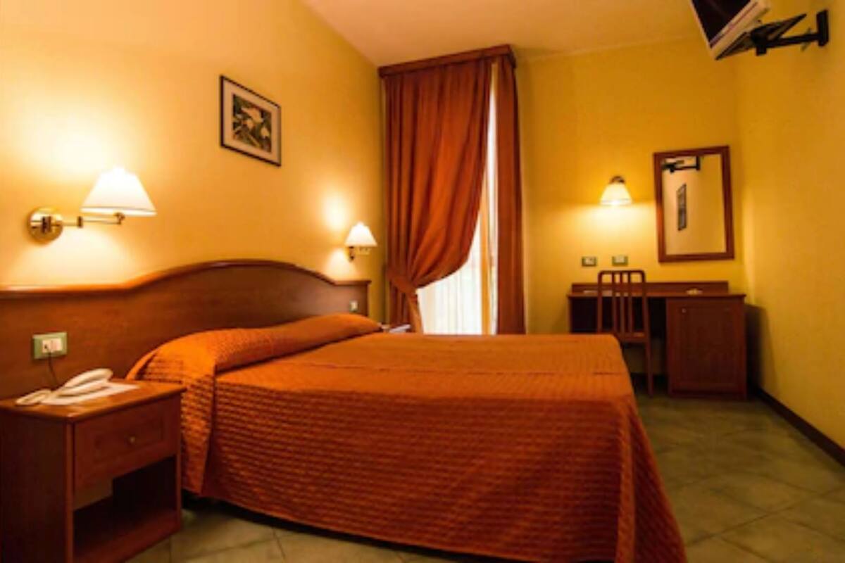 Een hotelkamer met een bed, nachtkastjes, een bureau en een stoel.