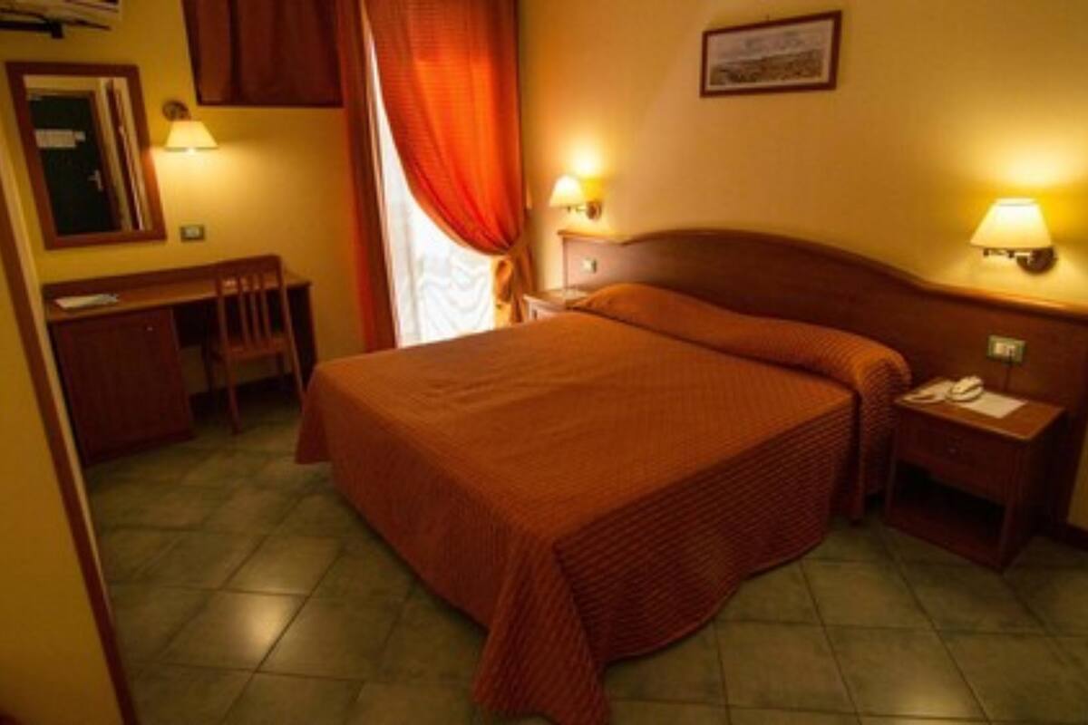 Een hotelkamer met een groot bed, een bureau, een stoel en twee bedlampjes.