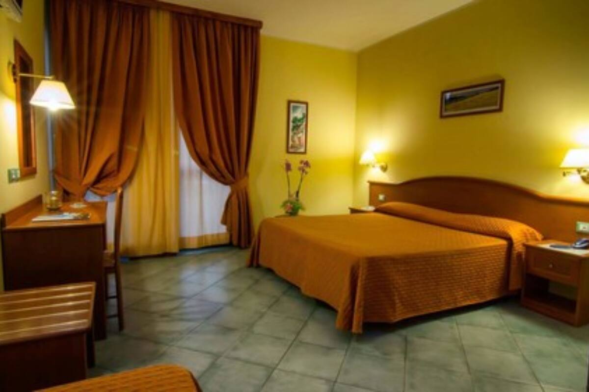 Een hotelkamer met een bed, een bureau, een stoel, een nachtkastje en een lamp.