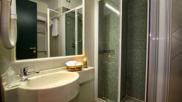 Baño con lavamanos, espejo y cabina de ducha.