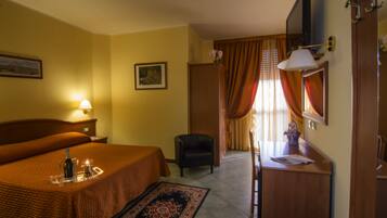 Ein Hotelzimmer mit Bett, Schreibtisch, Stuhl, Fernseher und einer Tür.