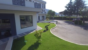A modern residential building with a well-maintained lawn, a curved driveway, and a parking area.