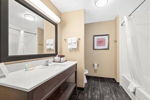 A modern bathroom with a large mirror, dual sinks, a shower, and a toilet.