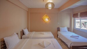 A hotel room with two single beds, a hanging light fixture, and a window with a view. - At Smile Oasis Houses (Bangkok)