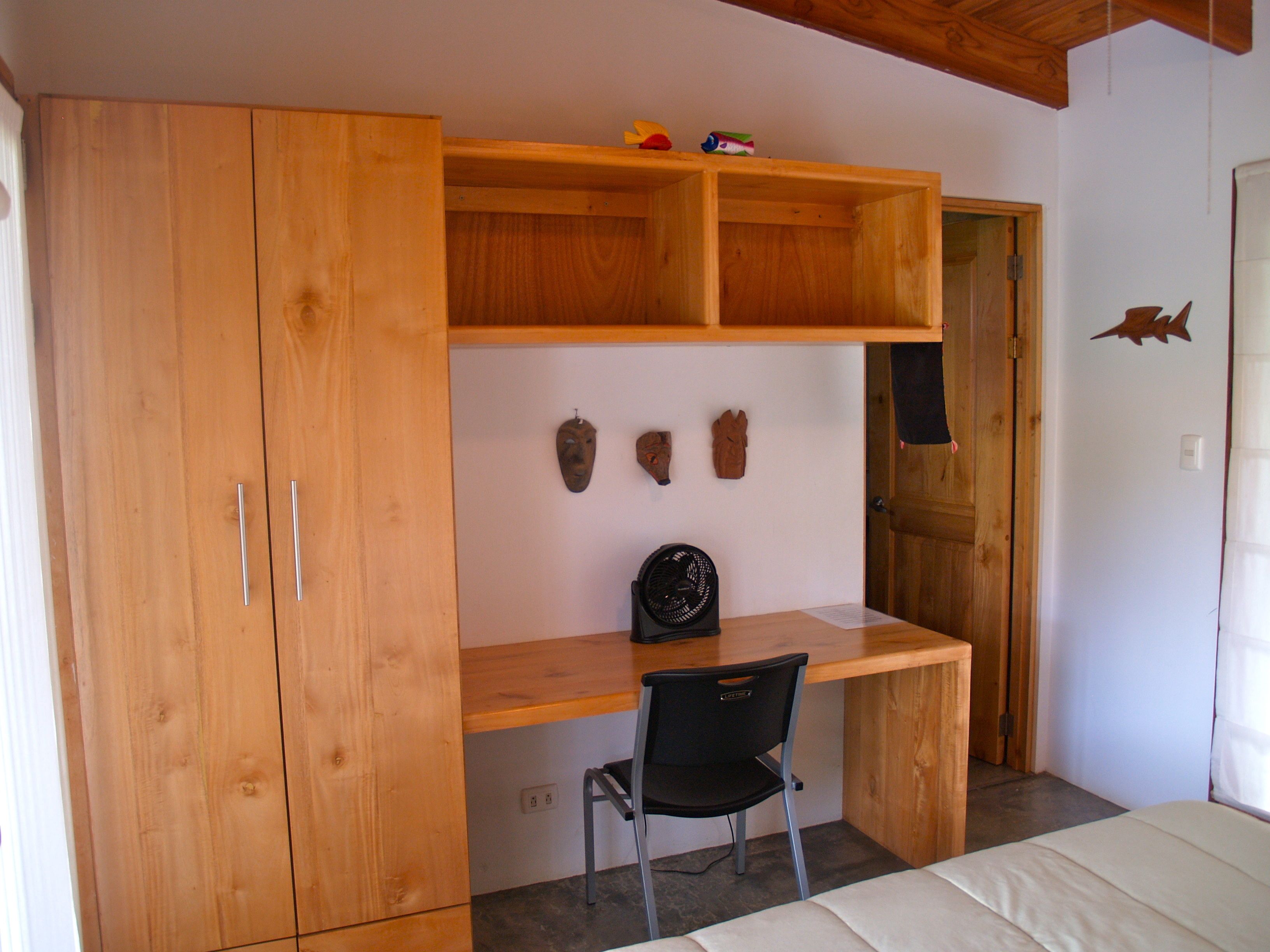 A bedroom with a wooden desk, a chair, a bed, and a wardrobe.
