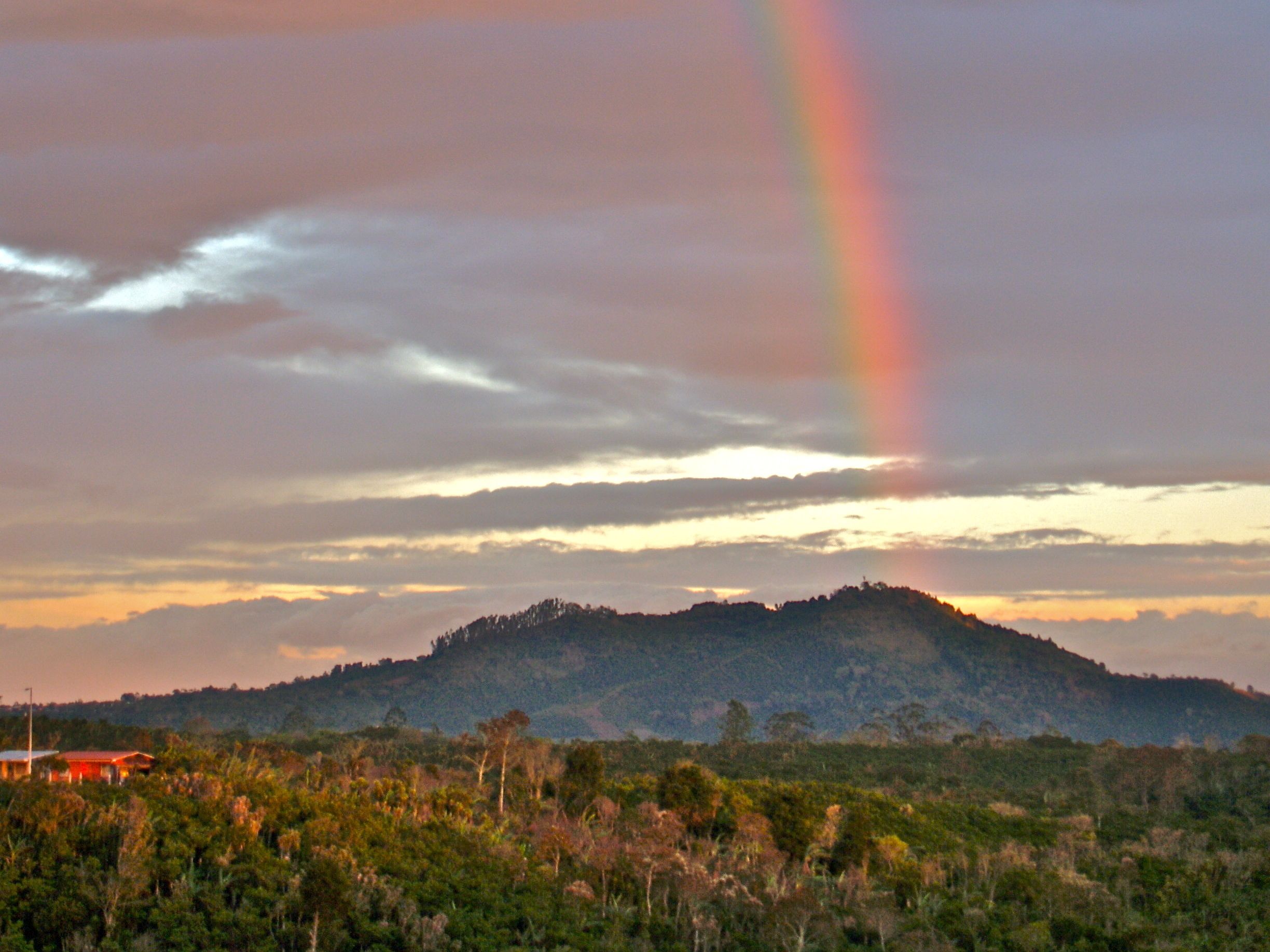 Eine Landschaft mit einem Hügel und einem Regenbogen.