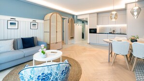 A modern living room with a sofa, coffee table, and a dining area with chairs. - SEETELHOTEL Ostseeresidenz Heringsdorf (Heringsdorf)