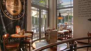 A restaurant interior with a large window, wooden furniture, and a sign reading "USE DOMER BRAUHAUS". - SEETELHOTEL Ostseeresidenz Heringsdorf (Heringsdorf)