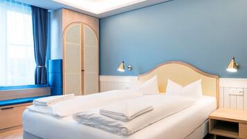 Una habitación de hotel con una cama grande, dos mesitas de noche, un armario y una ventana con cortinas.