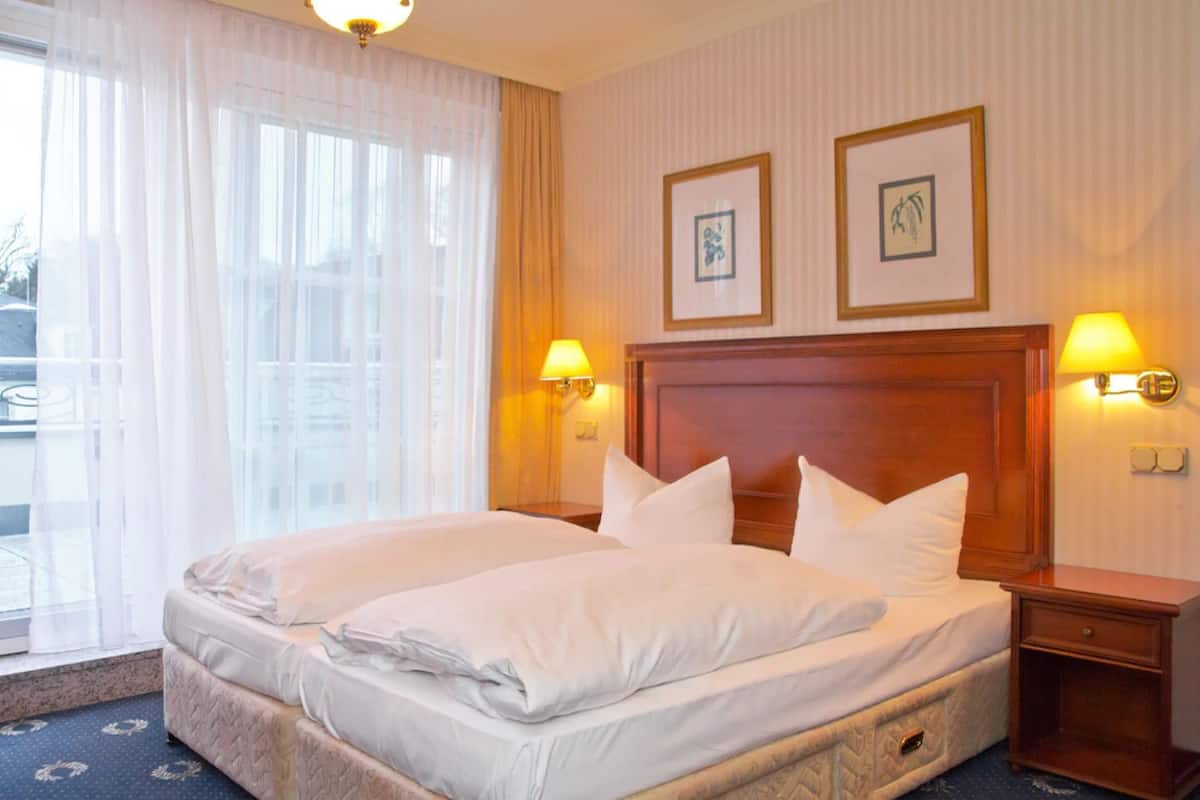 A hotel room with a large bed, two bedside lamps, and two framed pictures on the wall.