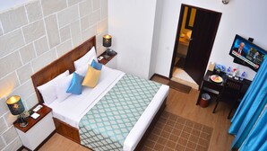 A hotel room with a bed, nightstands, a television, and a bathroom visible through an open door. - Unique Cottages (Nuwara Eliya)