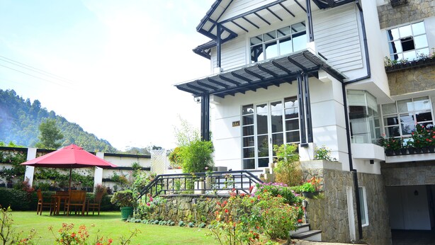 A two-story house with a balcony, a garden, and a red umbrella. - Unique Cottages (Nuwara Eliya)