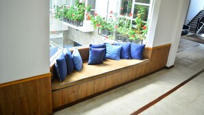 A seating area with a bench and blue cushions, overlooking a balcony with potted plants and flowers. - Unique Cottages (Nuwara Eliya)