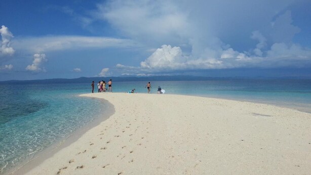 A beach with clear turquoise water, a sandy shore, and a few people. - Little Mermaid Dive Resort (Daanbantayan)